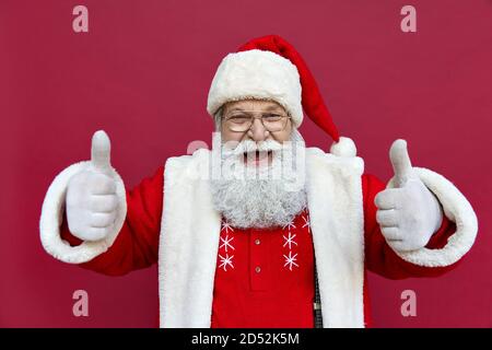 Happy Santa Claus zeigt Daumen nach oben isoliert auf rotem Hintergrund. Stockfoto