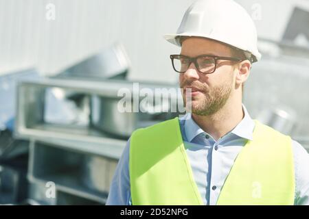 Portrait von jungen Bauingenieur trägt Helm wegschauen, während Auf der Baustelle stehen Stockfoto