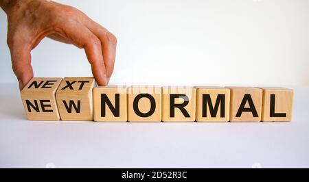 Die Hand dreht Würfel und ändert die Wörter „New normal“ in „Next normal“. Covid-19-Konzept nach einer Pandemie. Schöner weißer Hintergrund, Kopierbereich. Stockfoto