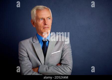 Studio Portrait von älteren Mann mit Anzug und grauen Hintergrund stehen. Stockfoto