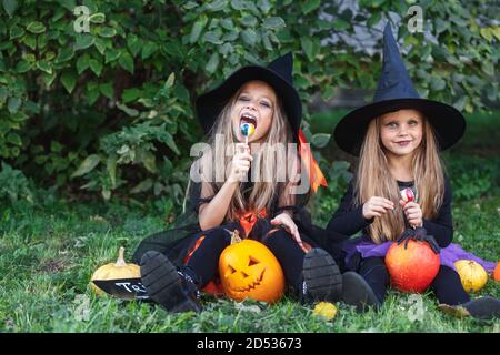 Zwei lustige kleine Mädchen in Hexenkostümen essen Halloween Süßigkeiten Stockfoto