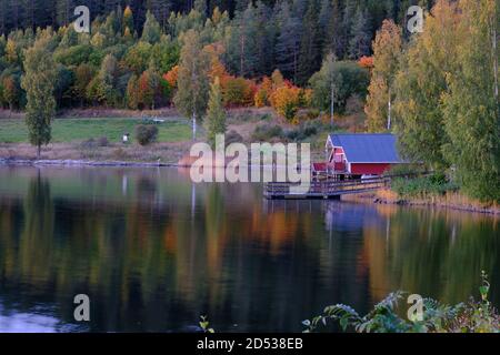 Rotes Bootshaus mit Wald in Herbstfarben im Hintergrund Stockfoto