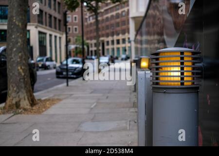 Grauer Straßenbollard und Beleuchtung mit unscharfem Hintergrund Straßenszene Stockfoto