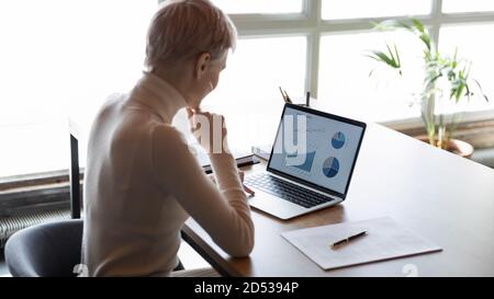 Weibliche Angestellte arbeiten am Laptop und analysieren Finanzgraph Stockfoto