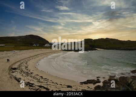 Achmelvich Beach, North Coast 500, Scotland, UK mit einsamem Paar, das bei Sonnenuntergang auf Sand läuft Stockfoto