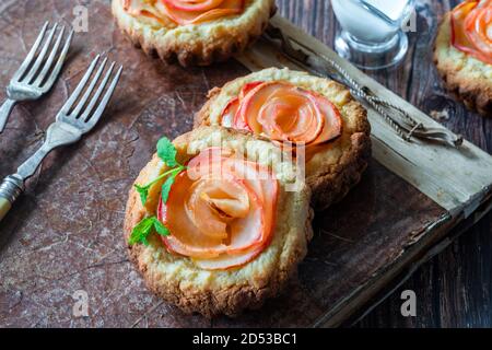 Mini Mandeltörtchen mit Apfelscheiben in einer Rose angeordnet Stockfoto