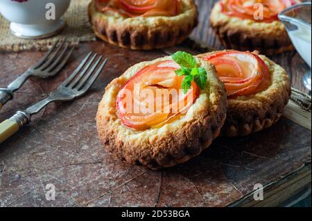 Mini Mandeltörtchen mit Apfelscheiben in einer Rose angeordnet Stockfoto