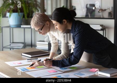 Multirassische weibliche Kollegen arbeiten im Büro mit Papierdokumenten Stockfoto