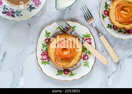 Mini Mandeltörtchen mit Apfelscheiben in einer Rose angeordnet Stockfoto