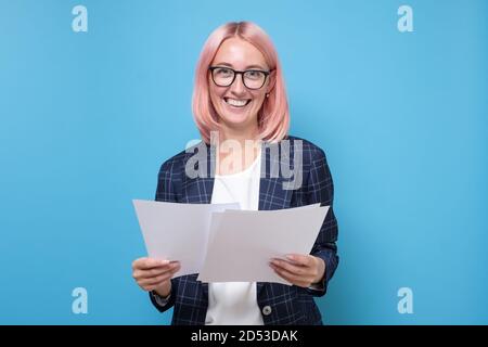 Glückliche schöne junge Geschäftsfrau stehend und hält Papiere Stockfoto