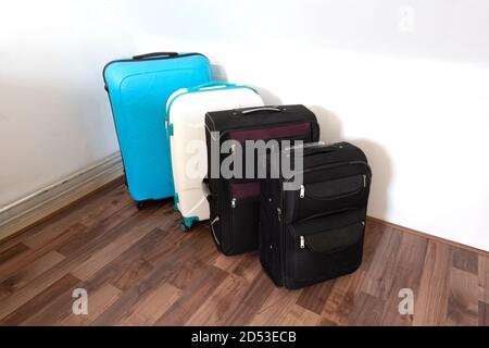 Verschiedene Koffer oder Reisetaschen in einer Reihe nahe weißer Wand, moderne Gepäcktaschen für den Tourismus Stockfoto