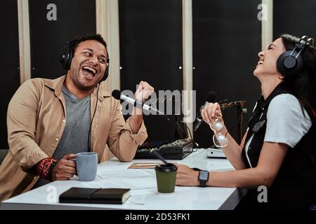 Portait von zwei Radio-Moderatoren, Mann und Frau lachen, während sie miteinander reden, moderieren eine Live-Show im Studio Stockfoto