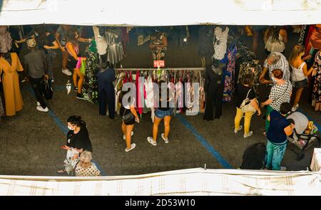 Hochwinkel Blick auf den wöchentlichen Stadtmarkt mit Mädchen und Frauen Auswahl Kleidung an den Ständen im Sommer, Siena, Toskana, Italien Stockfoto