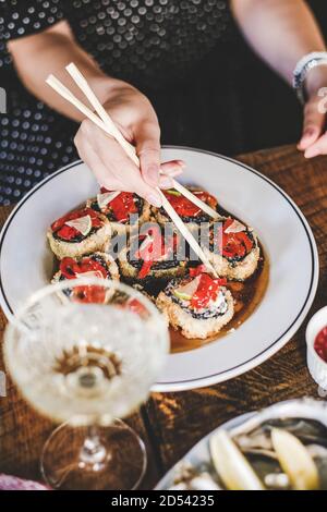 Mädchen essen Sushi mit Essstäbchen im japanischen Fischrestaurant Stockfoto