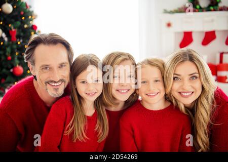 Foto der ganzen Familie fünf Leute sammeln drei kleine Kinder Kuscheln Sie sich mit lächelndem Lächeln tragen Sie roten Pullover im dekorierten Wohnzimmer Weihnachten Vorbereitung immergrün Stockfoto