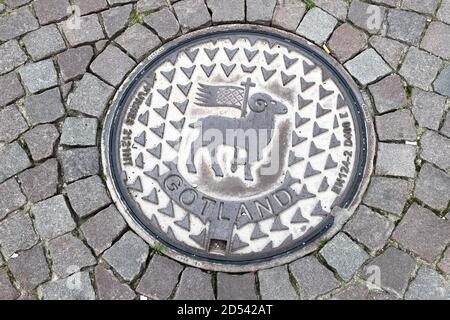 Visby, Schweden - 4. Oktober 2020: Eine Schachtabdeckung mit dem Wappen der schwedischen Provinz Gotland. Stockfoto