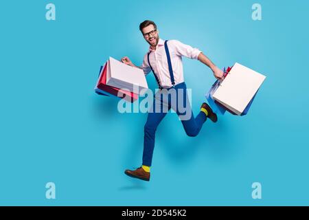 In voller Länge Profil Foto von schönen Business-Mann tragen Taschen Sprung hoch kaufen Urlaub Zeug Einkaufszentrum Laden Mall tragen Specs Shirt Hosenträger Stockfoto