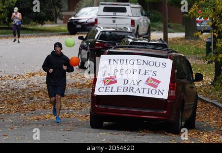 St. Louis, Usa. Oktober 2020. Ein Jogger läuft an einem geparkten Auto vorbei, an dem ein Schild der indigenen Völker angebracht ist, wo ein Picknick stattfindet, neben dem, wo am Columbus Day in St. Louis am Montag, dem 12. Oktober 2020, eine Statue von Christoph Kolumbus im Tower Grove Park stand. Foto von Bill Greenblatt/UPI Kredit: UPI/Alamy Live News Stockfoto