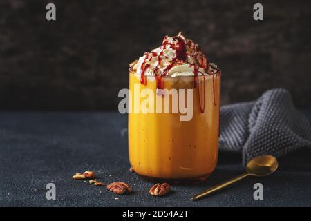Kürbis-Smoothie serviert mit Schlagsahne und Karamell im Glas. Nahaufnahme Stockfoto