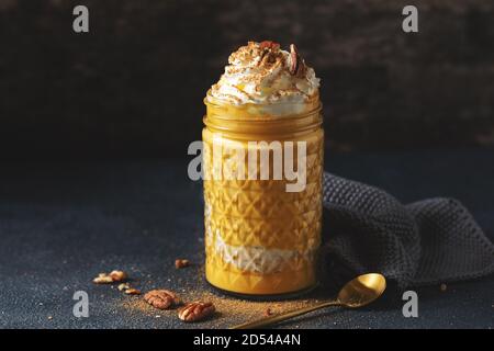 Kürbis-Smoothie serviert mit Schlagsahne und Karamell im Glas. Nahaufnahme Stockfoto