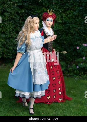 MÜNCHEN, DEUTSCHLAND - 12. Sep 2020: Cosplayer als Figuren aus Alice im Wunderland. Alice wird von der roten Königin gehalten und kontrolliert Stockfoto