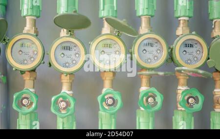 Reihe von Industrierohrleitungen und Armaturen mit grünen Rädern auf Graue Wand zur Überprüfung des Standardwasserstands in Der Schlafsaal für überprüfen Sie den Preis Stockfoto