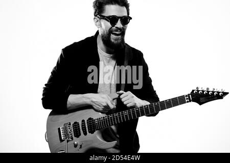 Ein Mann mit einer Gitarre Emotionen Musik Spiel Performance Leder Jacke Sonnenbrille Licht Hintergrund Stockfoto