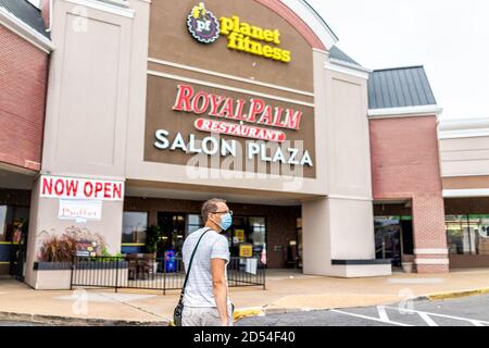 Sterling, USA - 9. September 2020: StoreFront am Strip Mall plaza mit Menschen Mann Person in Maske zu Fuß in Richtung Planet Fitness-Zeichen und jetzt geöffnet duri Stockfoto