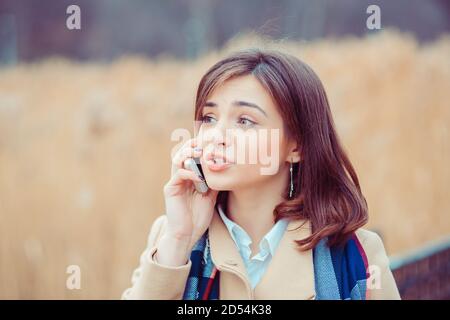 Skeptische Frau am Telefon zu entscheiden, was im Freien zu beantworten Im Parkhintergrund Stockfoto
