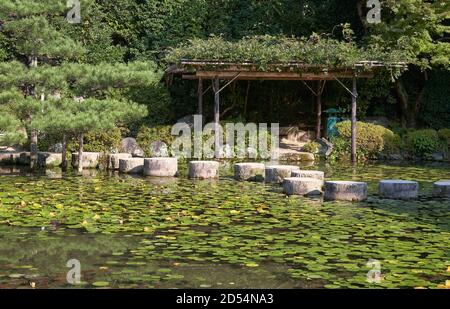 Garyu Brücke durch den Soryu-ike Teich bedeckt mit Seerosen und Pavillon im mittleren (Naka Shin-en) Garten des Heian-jingu Schrein. Kyoto. Japan Stockfoto