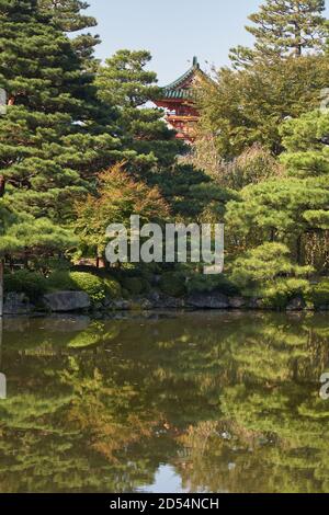 Der Blick auf Zinnober Turm von Heian-jingu Schrein durch die Pinien umgeben die Seiho-ike Teich in East Shin-en Garten. Kyoto. Japan Stockfoto