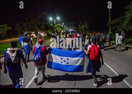 San Pedro Sula, Honduras. Januar 2020. Am ersten Tag ihrer Reise an die US-Grenze marschieren Migranten mit einer honduranischen Flagge gegen 4 Uhr morgens zur Grenze Guatemalas. Migranten fliehen vor extremer Armut und Bandengewalt, in der Hoffnung, ein besseres Leben in den USA zu finden.Sie müssen über 3,000 Meilen durch Guatemala und Mexiko reisen, oft mit nichts als der Kleidung auf dem Rücken, um die Grenze in Tijuana, Mexiko zu erreichen, wo ihr Schicksal unentschieden ist. Kredit: Seth Sidney Berry/SOPA Images/ZUMA Wire/Alamy Live Nachrichten Stockfoto