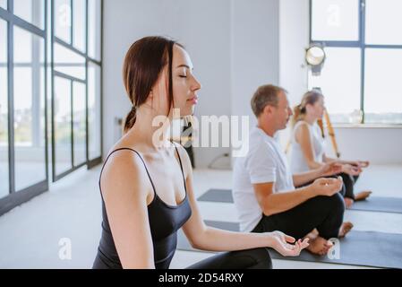 Junge Frau im Yoga-Kurs meditiert mit geschlossenen Augen Stockfoto