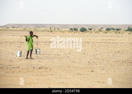 Junger Junge mit Wasser in in-Gall, in der Nähe von Agadez, Niger. September 1996. Stockfoto