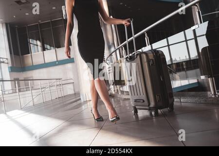 Frau, die einen Koffer durch den Flughafen trägt Stockfoto