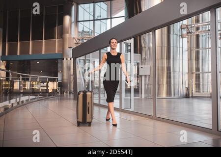 Frau, die einen großen Koffer durch den Flughafen trägt Stockfoto