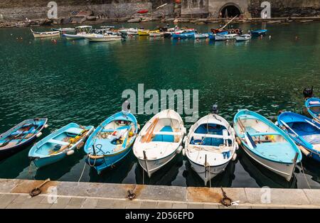 Tolle Nahaufnahme des Hafens von Vernazza in der Küstenregion Cinque Terre. Auf dem seichten türkisfarbenen Wasser treiben viele kleine Boote in einem... Stockfoto