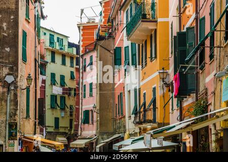 Schöne Nahaufnahme der Hauptstraße von Vernazza, Via Roma in der Region Cinque Terre. Die belebte Straße hat die typischen bunten Turmhäuser mit grünen... Stockfoto