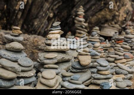 Schöne Nahaufnahme von mehreren gestapelten Steinen in einer Reihe auf einem auftauchenden Felsen am Eingang des zerklüfteten Kiesstrandes an der Ostküste von... Stockfoto