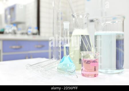 Selektiver Fokus von farbigen flüssigen Chemikalien in Glasbecher, Kolben und Rohr. Chemie Laborklasse Experiment Hintergrund mit Kopierraum. Stockfoto