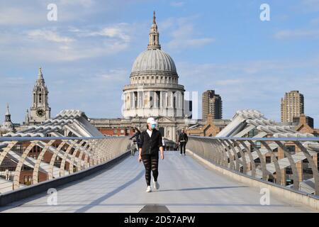 Eine Frau mit einer schützenden Gesichtsmaske geht über die Millennium Bridge mit der St. Paul's Cathedral im Hintergrund. London, Großbritannien 2020. Stockfoto