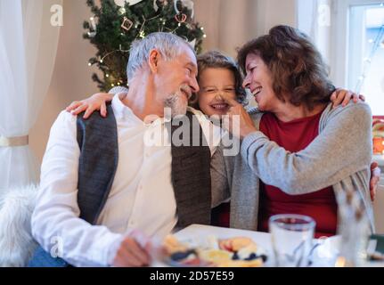 Seniorenpaar mit kleiner Enkelin drinnen zu Weihnachten, Spaß haben. Stockfoto
