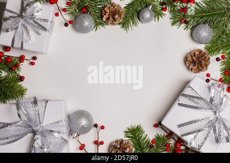 Weihnachtsbaum mit Schnee, Tannenzapfen, roten Beeren und Geschenkboxen auf weißem Hintergrund mit Kopie Raum Stockfoto