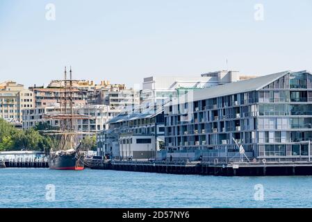 Das große Schiff James Craig, das im Hafen von Sydney neben dem Hauptquartier der Sydney Heritage Fleet und den nahe gelegenen Sydney Waterside Apartments vor Anker liegt Stockfoto