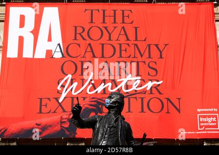 London, Großbritannien. - 5. Oktober 2020: Eine maskierte Statue vor einem Banner für die traditionelle Royal Academy Summer Exhibition, die wegen der Coronavirus-Pandemie bis Oktober verschoben wurde. Stockfoto