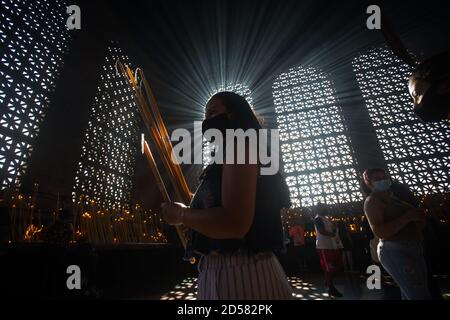 Aparecida, Brasilien. Oktober 2020. Ein Gläubiger trägt Kerzen und betet im Kerzenraum der Basilika von Nossa Senhora Aparecida, während des Tages von Nossa Senhora Aparecida, der schutzpatronin Brasiliens. Zum ersten Mal in der Geschichte der Basilika mussten wegen der Corona-Pandemie die Messen hinter verschlossenen Türen oder in Anwesenheit einer kleinen Anzahl von Menschen gefeiert werden. Quelle: Fernando Souza/dpa/Alamy Live News Stockfoto