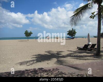 Leerer Sandstrand Kuta Beach Bali mit Sonnenliegen Sonnenschirm und Palme Stockfoto