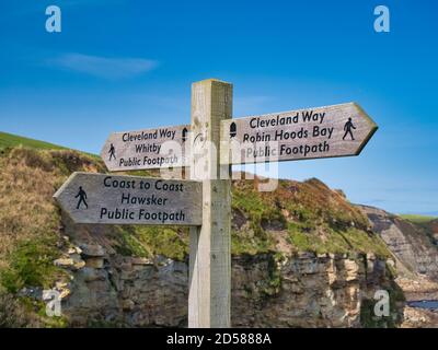 Ein Holzschild in der Nähe von Robin Hood's Bay markiert die Kreuzung Des Cleveland Way National Trail und der England Coast Zum Küstenpfad Stockfoto