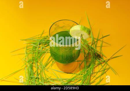 Weizengras, Triticum aestivum Pflanze eine super potente Gesundheit Lebensmittel. Glas mit frischem Saft im Vordergrund Minzblätter und Gurkenscheibe auf dem Stockfoto