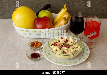Obstschale mit Birne, rotem Apfel, grünem Apfel, Banane und Kanarienmelone auf einem Teller angeordnet. Schale mit Obstsalat, Mandel- und Safranschale. Glas Stockfoto